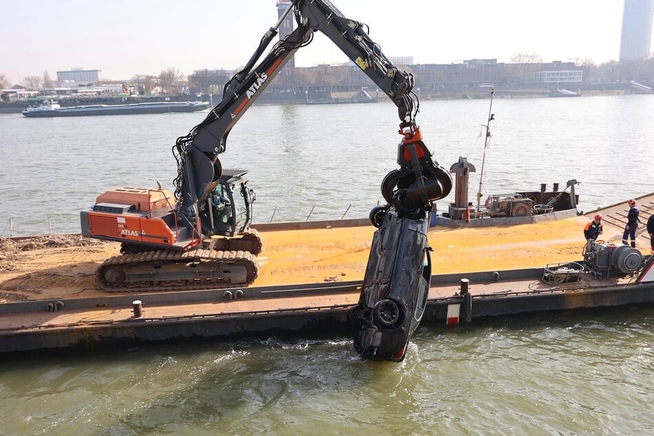Die Einsatzkräfte setzen einen Kran ein, um den versunkenen Wagen aus den Tiefen des Rheins zu holen.