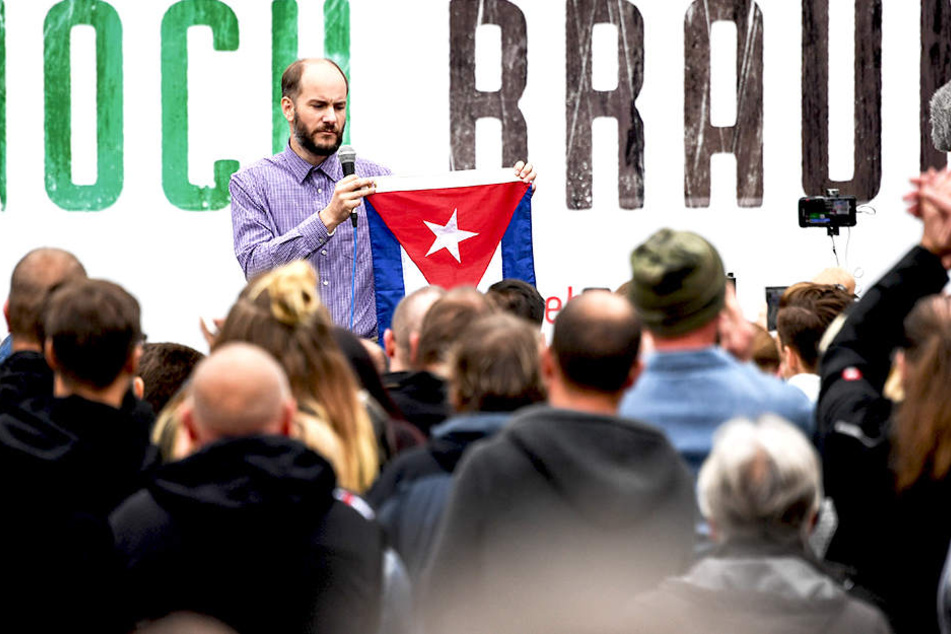 Bei der Kundgebung von "Pro Chemnitz" hält Martin Kohlmann eine Kuba-Flagge hoch.