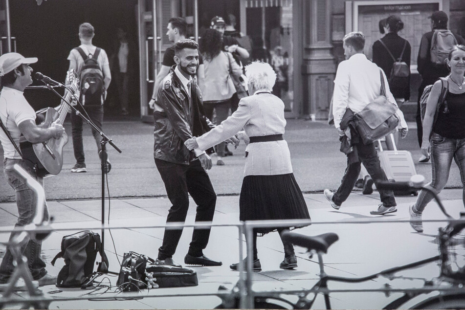 Alt und jung, schwarz und weiß, Lebensfreude pur: Die alte Dame tanzt mit einem Straßenmusiker.