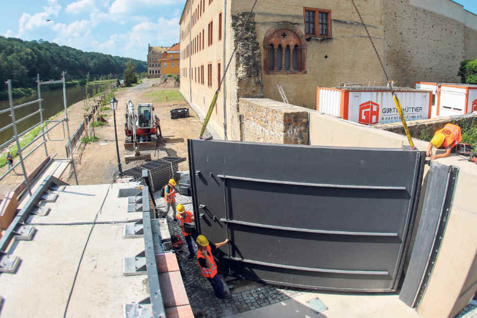 Mit einem Kran wird das letzte Tor für die Hochwasserschutzanlage eingehoben und damit die letzte Lücke in der Flutmauer geschlossen.