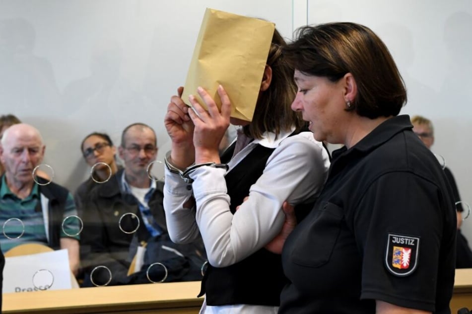 Mit verdecktem Gesicht wird die Angeklagte zum Auftakt eines Mordprozesses in den Gerichtssaal geführt.