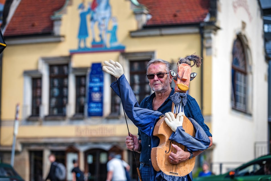 Rainer Petrovsky (74) 2021 vor dem Bräustübel: Damals winkte die Gitarrenpuppe in seinem Arm zur Begrüßung, nun bedeutet die Geste Abschied.