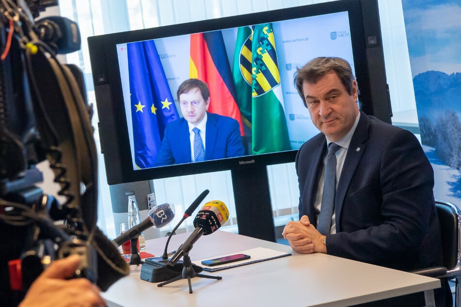 Markus Söder (r, CSU), Ministerpräsident von Bayern, nimmt in der Staatskanzlei an einer Online-Pk von Bayern und Sachsen zur Covid-19-Allianz der beiden Bundesländer teil. Auf dem Bildschirm ist Michael Kretschmer, (CDU) Ministerpräsident von Sachsen zu sehen.