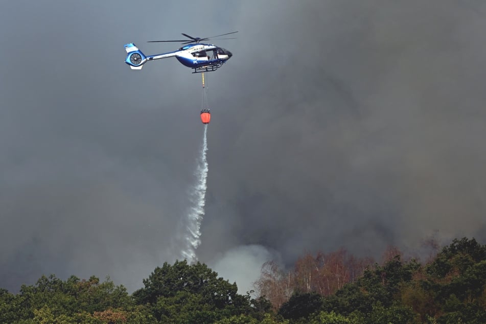 Ein Polizeihubschrauber mit einem Löschsack versucht, die Flammen aus der Luft unter Kontrolle zu bekommen.