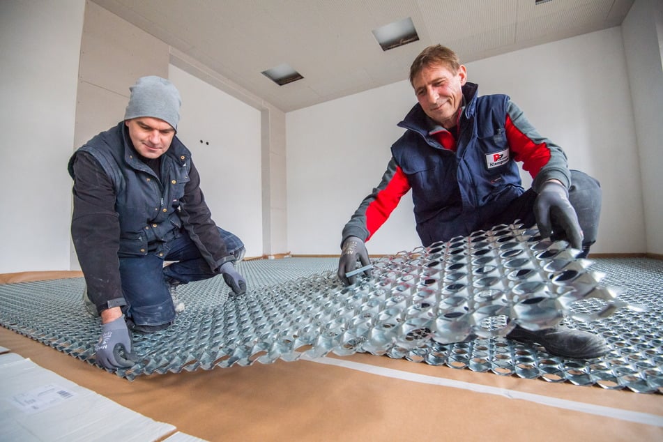 Raik Friedrich (l.) und Mike Rosenhahn verlegen in der Altstadt-Grundschule Lößnitz Wabenträgerplatten für die Fußbodenheizung.