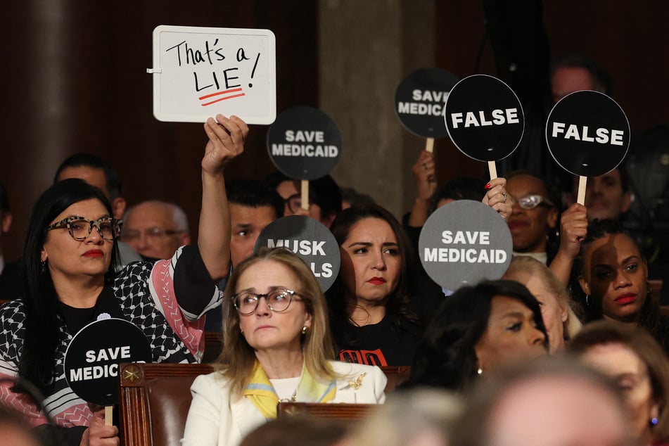 Numerous Democrats silently held up placards including "False," "Musk steals," and "That's a lie!"