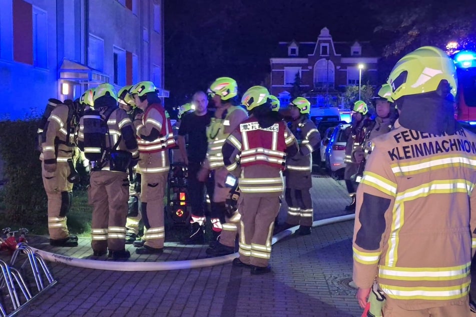 Feuerwehrleute drangen durch den verrauchten Hausflur zu einer Wohnung im Obergeschoss vor.