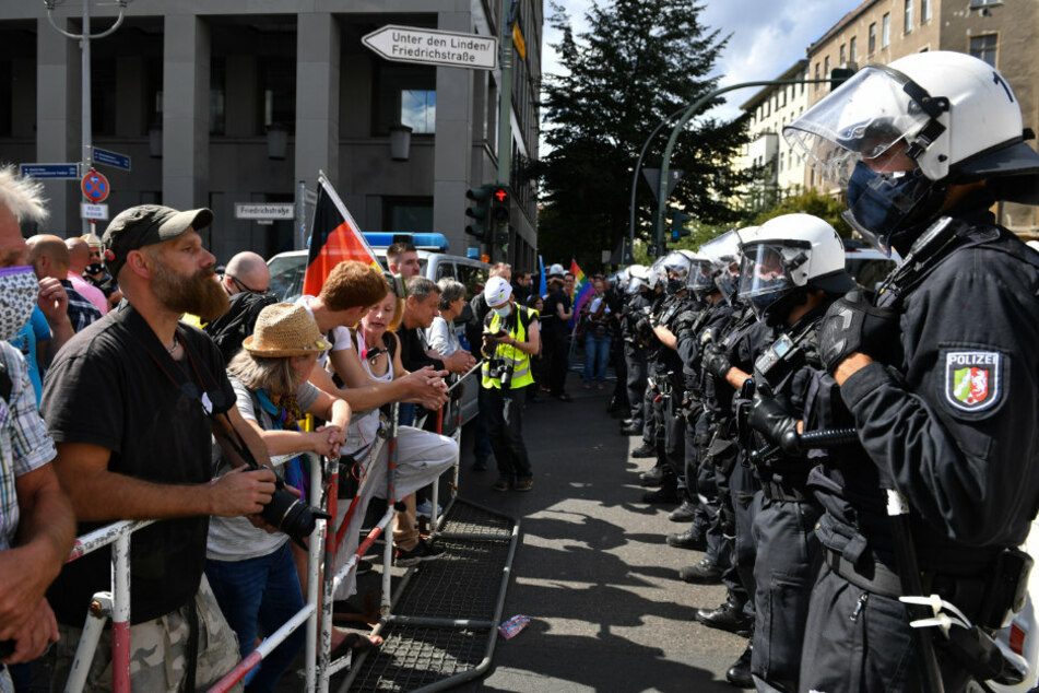 Eine Polizeikette steht an Absperrgittern den Teilnehmern gegenüber bei einer Demonstration gegen die Corona-Maßnahmen. F