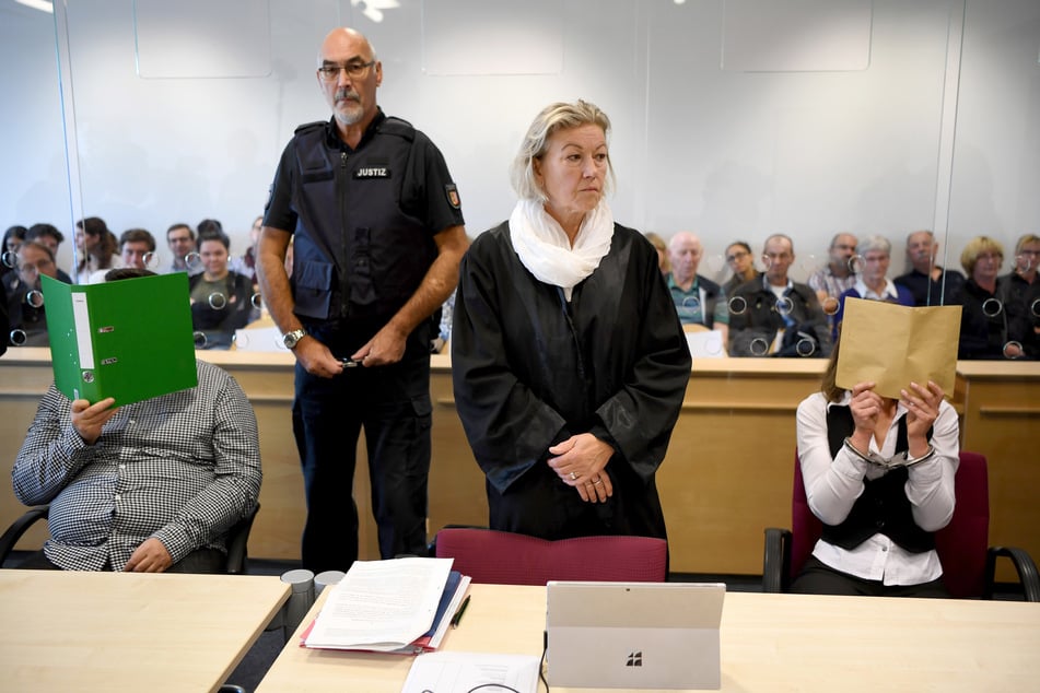 Mit verdeckten Gesichtern sitzen die Angeklagten zum Auftakt des Mordprozesses im Gerichtssaal.