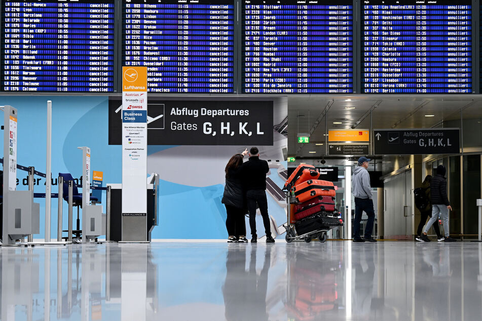 Passagiere stehen im Münchner Flughafen vor der Anzeigentafel. Der Betrieb wird hier am Dienstagvormittag erneut eingestellt.