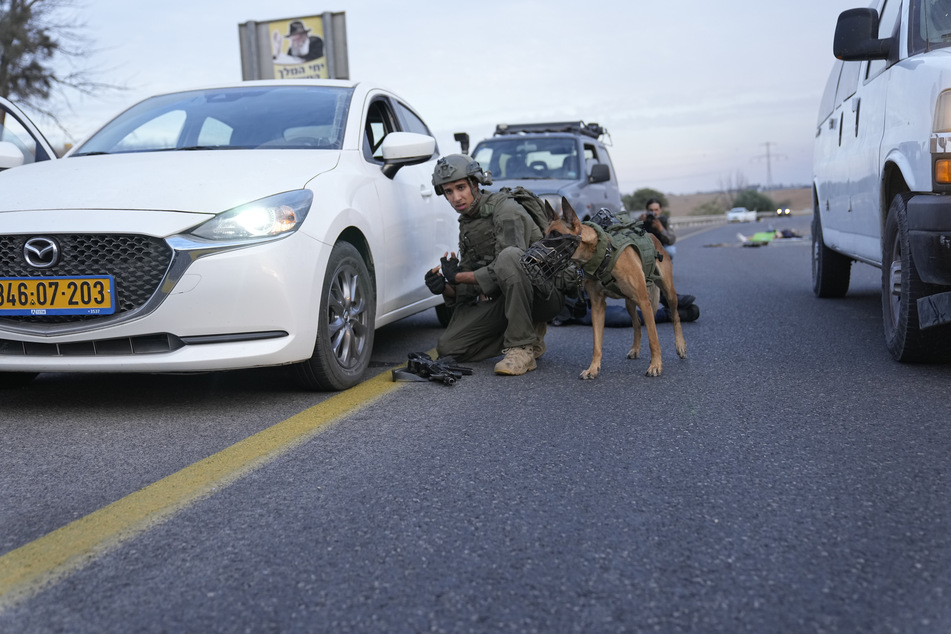 Ein israelischer Soldat in Sderot geht mit seinem Hund zwischen Autos in Deckung.