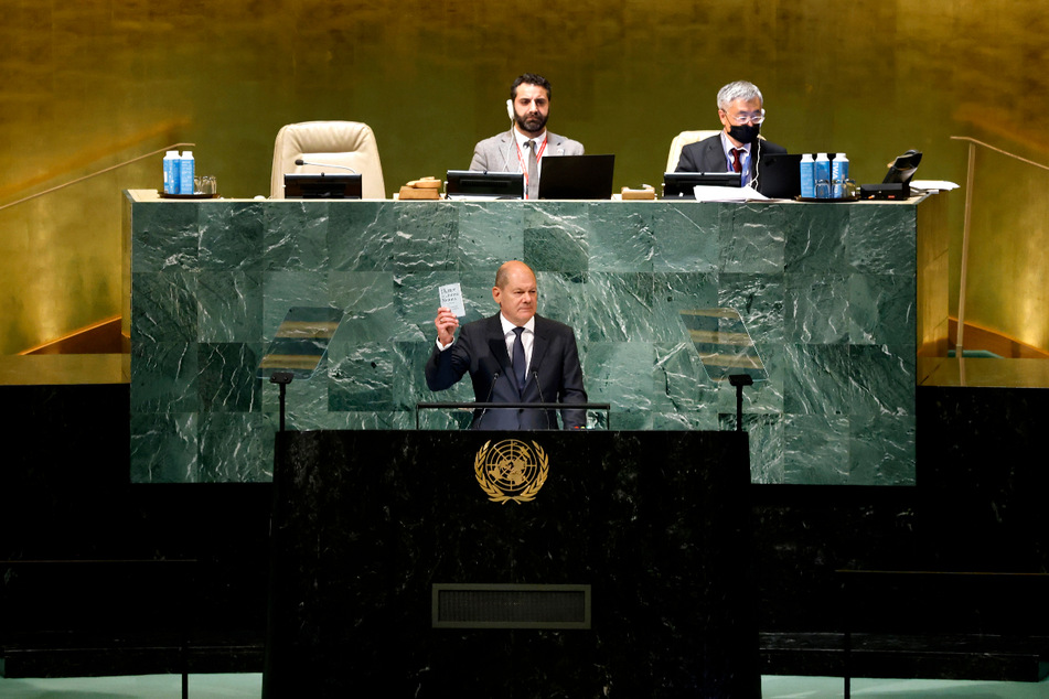 Olaf Scholz (64, SPD) hält während seiner Rede zu den Delegierten in der Generaldebatte bei der 77. Generalversammlung der UN ein Exemplar der Charta der Vereinten Nationen hoch.