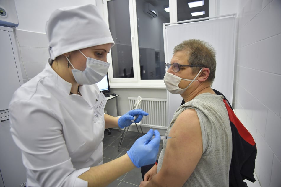 Eine medizinische Mitarbeiterin verabreicht einem Mann einen Corona-Impfstoff.