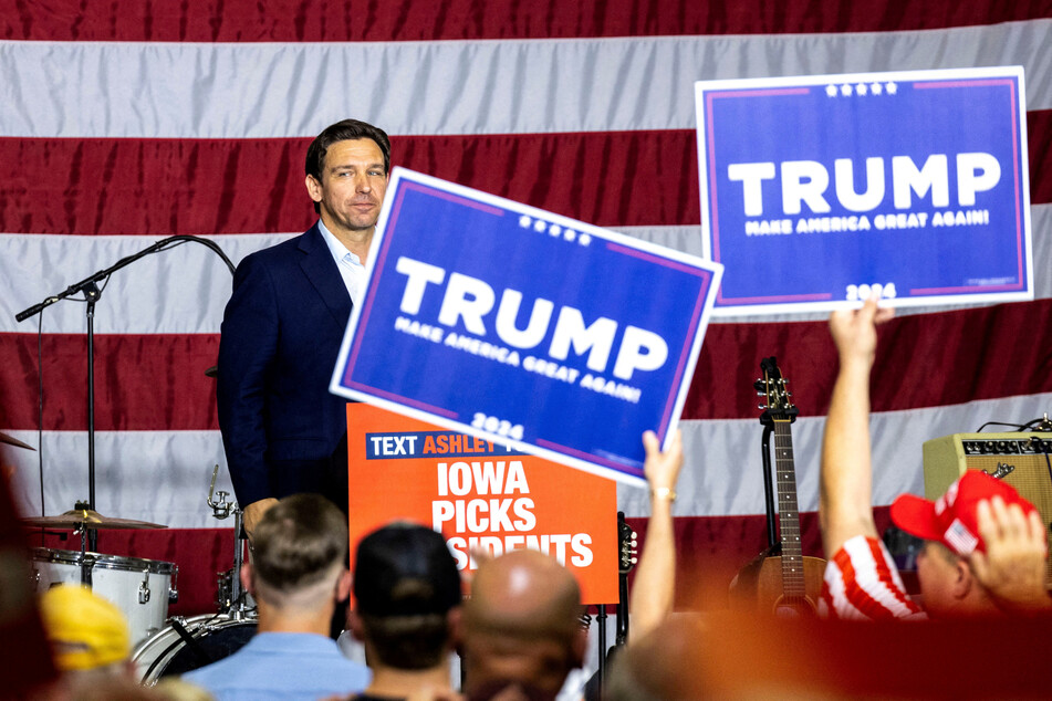 Republican presidential candidate and Florida Governor Ron DeSantis looks into the crowd in Cedar Rapids, Iowa, as supporters of former President Donald Trump hold up signs.