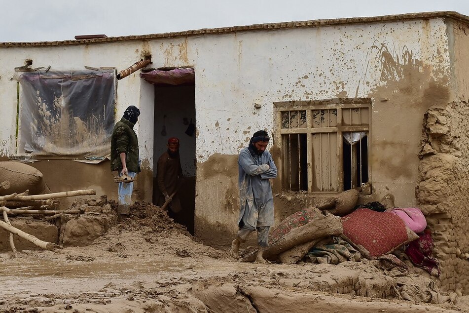Afghan men clear debris and mud from a damaged house following a flash flood after a heavy rainfall in Laqiha village of Baghlan-i-Markazi district in Baghlan province on May 11, 2024.