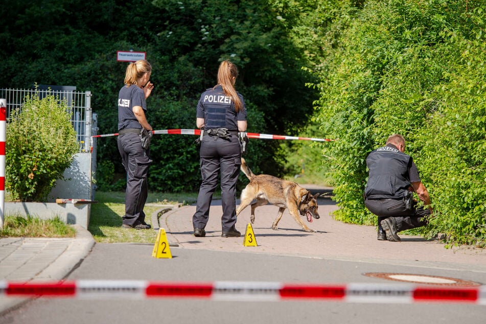 Zwei Polizistinnen, ein Polizist und ein Hund sind am Ort der Messerattacke in Erfurt. Der Bereich ist abgesperrt.