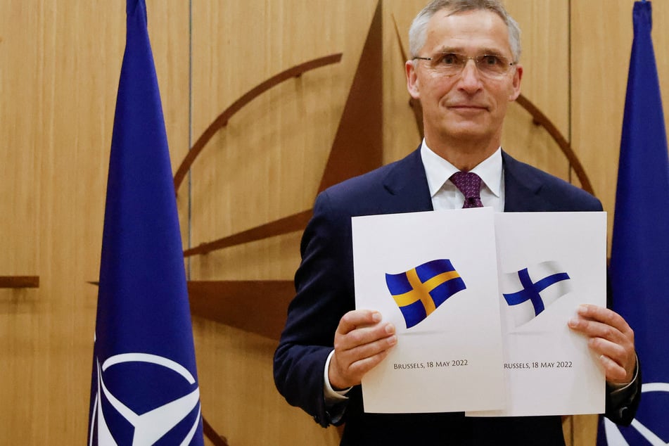 NATO Secretary General Jens Stoltenberg holding up papers with Swedish and Finish flags during the application ceremony on Wednesday.