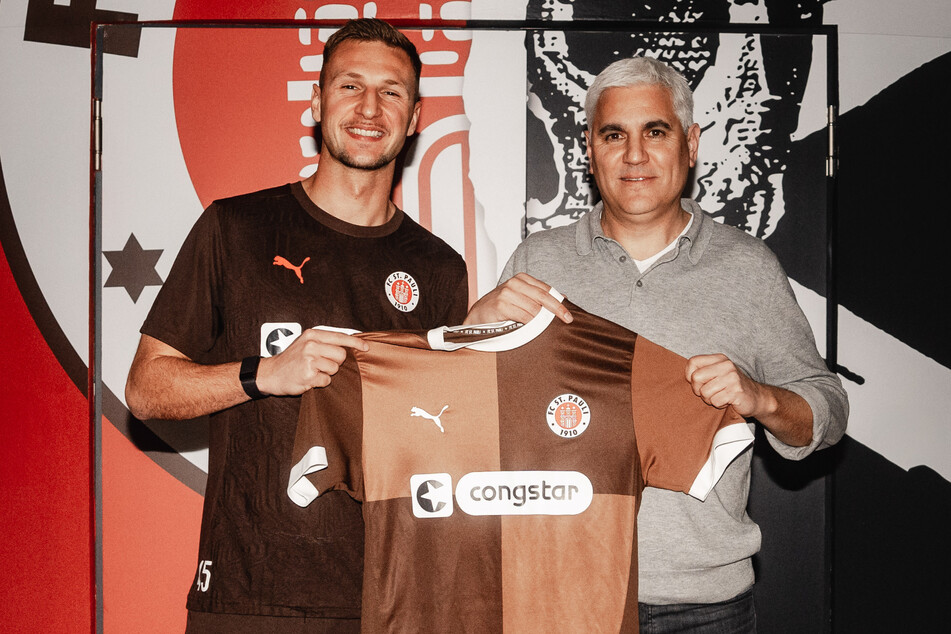 Neuzugang Siebe Van der Heyden (26) posiert mit St.-Pauli-Sportchef Andreas Bornemann (53, r.) und dem Trikot der Kiezkicker.