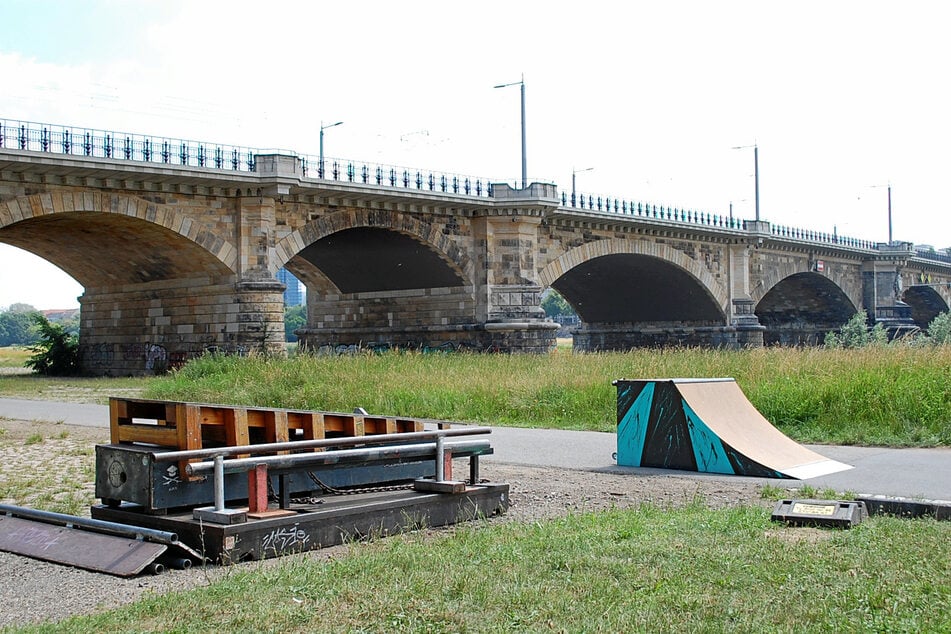 Die "Quarter" (kleine Schanze) rechts steht dauerhaft auf dem Pfad, kann aber bei Bedarf weggeschoben werden. Links sind die mobilen Hindernisse, die die Skateboarder nach dem Training wieder zusammenräumen.
