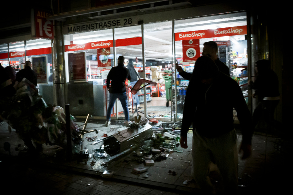 Menschen stehen vor einem geplünderten Geschäft in der Marienstraße. Bei Auseinandersetzungen mit der Polizei haben dutzende gewalttätige Kleingruppen die Innenstadt verwüstet und mehrere Beamte verletzt.