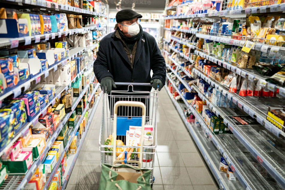 Ein Kunde kauft mit Mundschutz und Handschuhen am frühen Morgen in einem Berliner Supermarkt ein.
