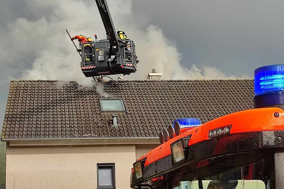 Einsatzkräfte löschen nach dem Blitzeinschlag den brennenden Dachstuhl.