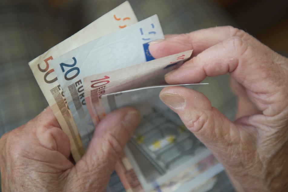Eine Frau zählt Geld. Der von der Bundesregierung geplante Corona-Zuschuss von 150 Euro für Empfänger von Grundsicherung ist aus Sicht des Sozialgerichts Karlsruhe zu gering und verfassungswidrig. (Symbolbild)