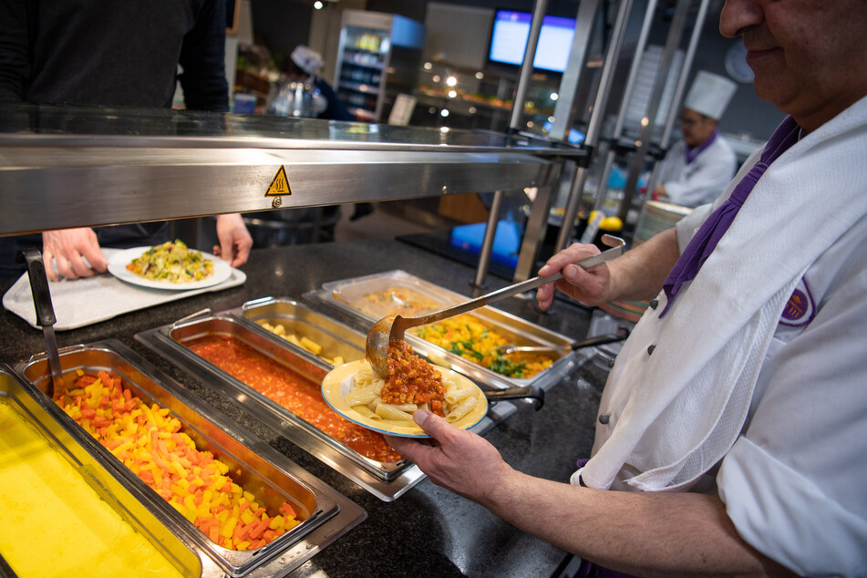 Ein Koch serviert in der veganen Mensa auf dem Campus der Technischen Universität Berlin ein veganes Gericht.