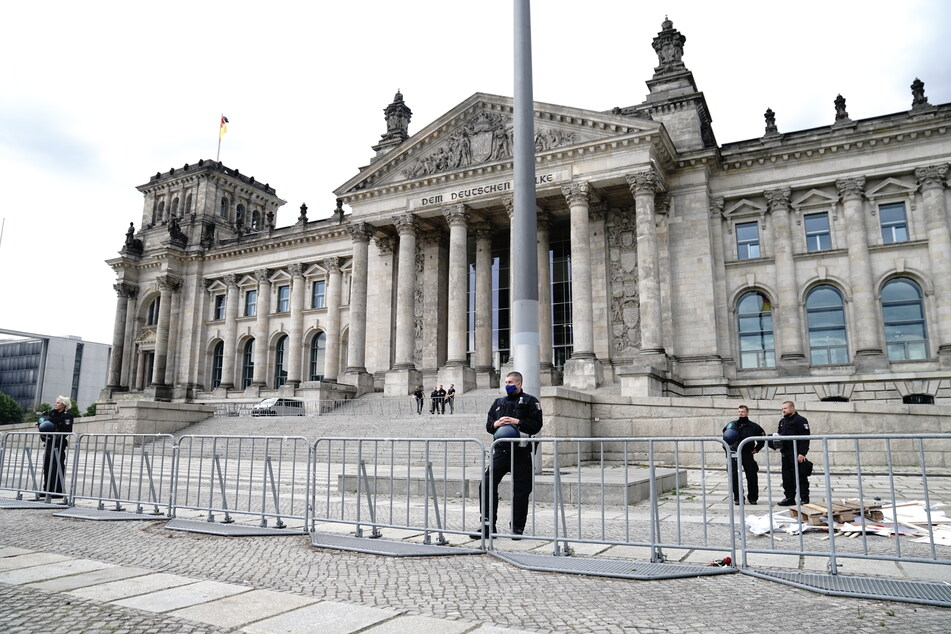 Polizeibeamte sichern hinter Absperrzäunen das Reichstagsgebäude.