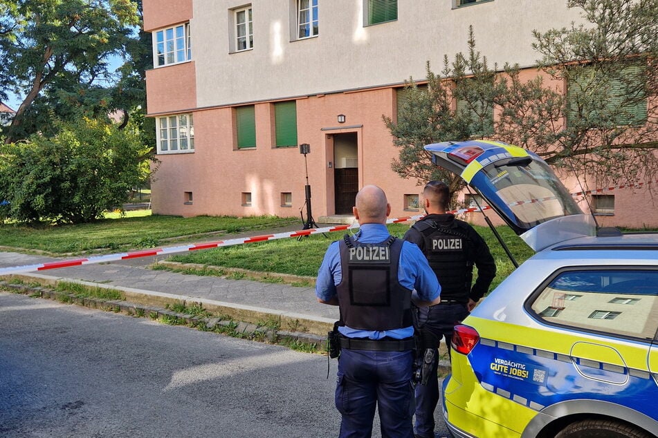 Polizisten bewachen den Eingang des Hauses, in dem es zu der Bluttat kam. Kriminaltechniker sichern derweil in der Erdgeschosswohnung Spuren.