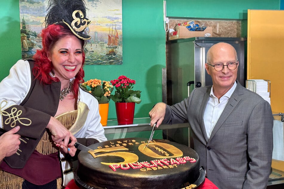 50 Jahre Pulverfass: Bürgermeister verteilt mit Burlesque-Star Torte an Bedürftige