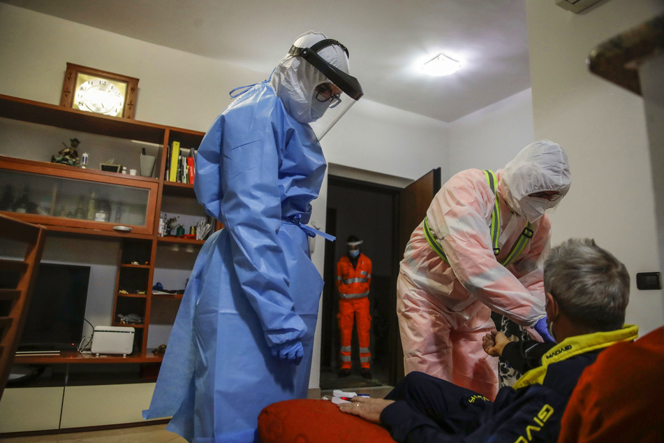 Der medizinische Mitarbeiter Ruggero Gariboldi (r) misst den Sauerstoffgehalt im Blut eines Mannes aus Monza, der unter Verdacht einer Corona-Infektion steht.