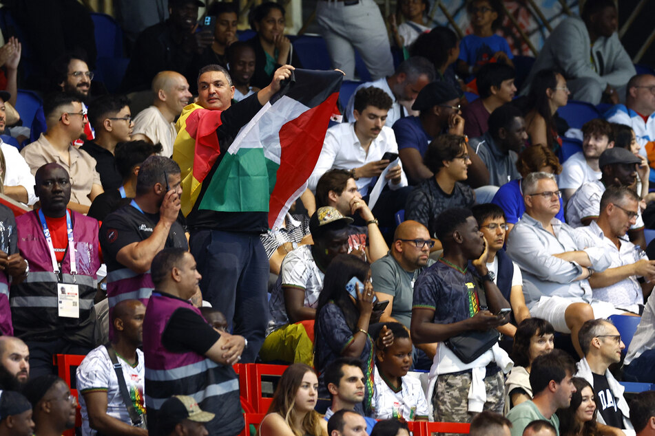 A Palestinian rights supporter holds a flag during Israel's Olympic soccer match against Mali.