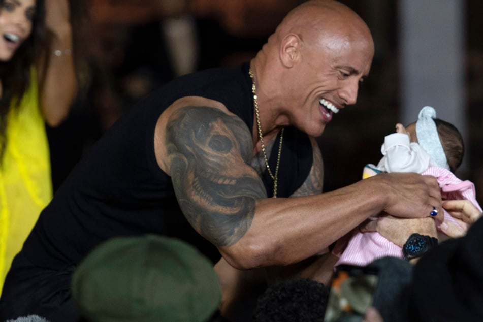 Dwayne Johnson carries a fan's baby at the premiere of Black Adam in Mexico City, Mexico on October 3.