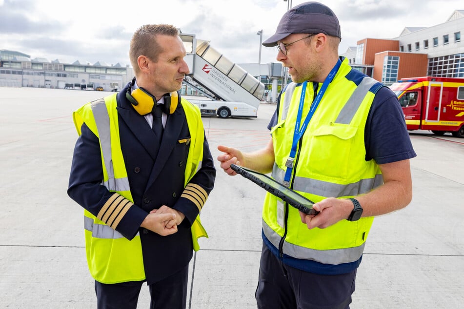 Engel der Lüfte trifft Engel mit Bodenhaftung: Ramp Agent Paul Löschner (28) informiert seinen Gegenpart Lufthansa-Flugkapitän Alexander Meier (51, l.) über aktuelle Passagier- und Gepäckdaten.