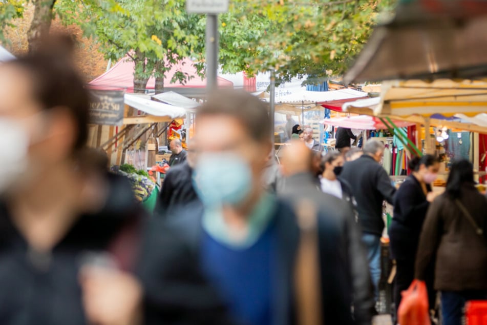 Menschen tragen Mund-Nasen-Bedeckungen und gehen in Berlin-Kreuzberg über den Markt am Maybachufer.