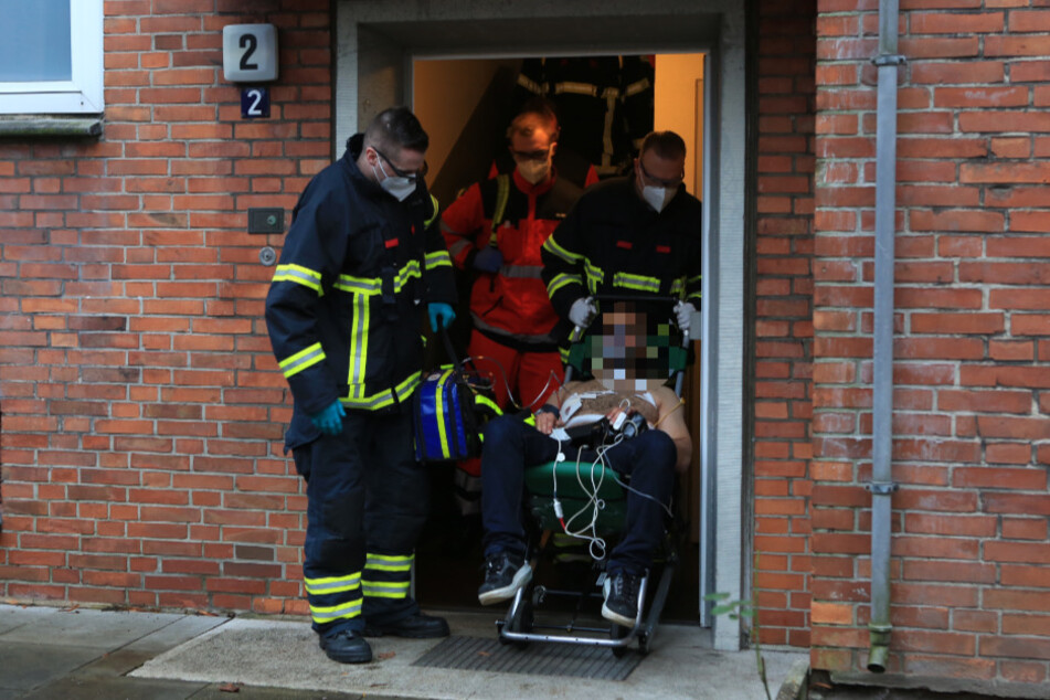 Rettungskräfte transportieren den Verletzten aus dem Haus.