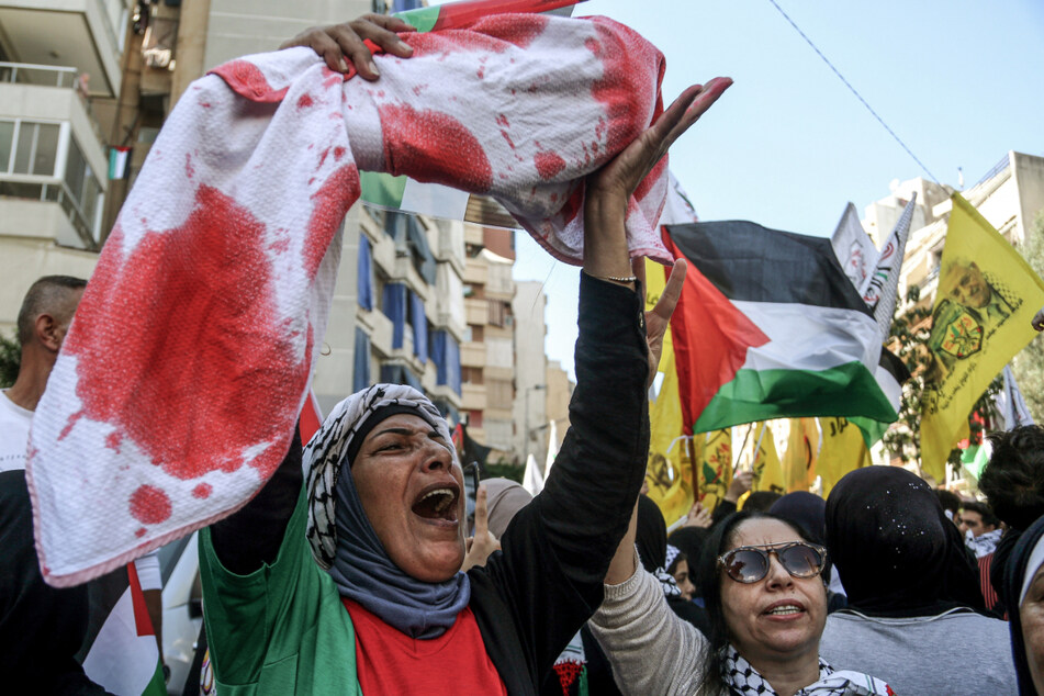 Eine Frau hebt während einer Demonstration zur Bekundung von Solidarität mit den Palästinensern in Beirut die Attrappe eines toten Kindes hoch, das in eine blutverschmierte Decke eingewickelt ist.