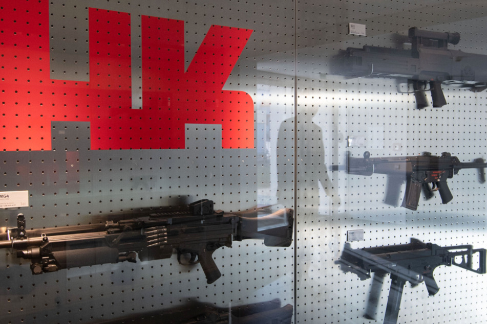 Das Logo des Waffenherstellers Heckler & Koch ist auf dem Firmengelände in Oberndorf an einer Präsentationswand neben Waffen zu sehen.