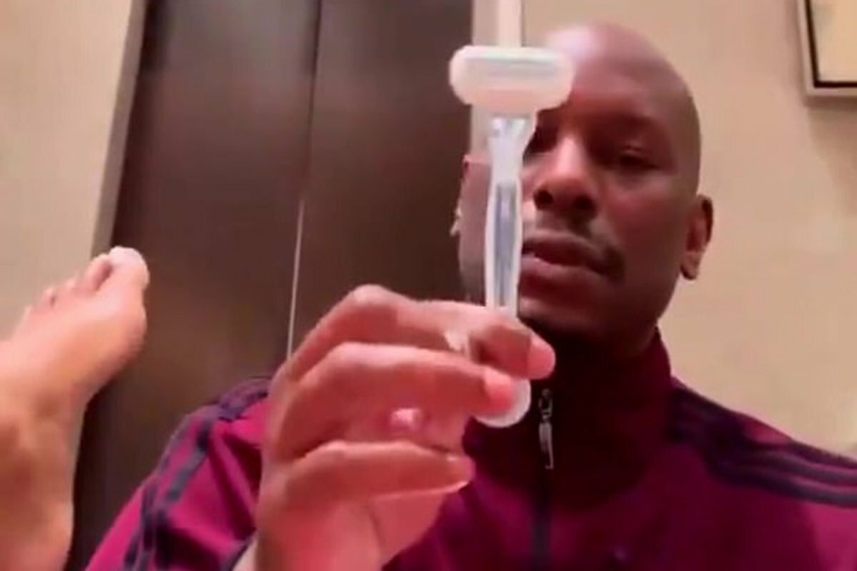 Tyrese holds a razor as he cleans up his girlfriend's private area.