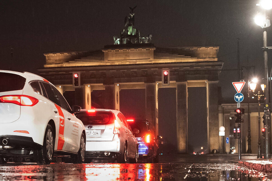 Autos stehen bei Schneeregen an einer Ampel am Brandenburger Tor. Der Deutsche Wetterdienst erwartet am Donnerstag gelegentlich leichten Regen, in der Nordhälfte Brandenburgs kann es teils zu Schneeregen kommen.