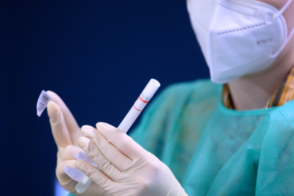 Eine Mitarbeiterin der Kassenärztlichen Vereinigung Sachsen beklebt in der Corona-Teststation am Flughafen Dresden International einen Abstrich für einen Coronavirus-Test mit einem Strichcode.