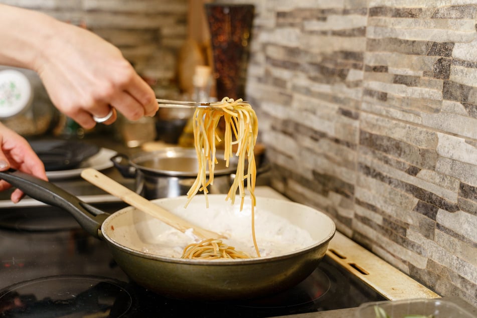 Die Nudeln für die Zitronenpasta werden nach dem Kochen im Topf in der Pfanne fertig gegart.