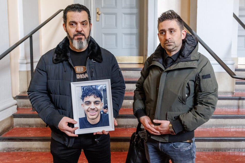 Nebenkläger Ali Ibrahim (l.) zeigt im Gericht neben seinem Anwalt Patrick Purbacher ein Bild des getöteten 15-Jährigen.
