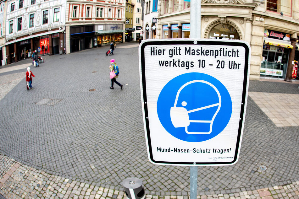 Ein Schild mit der Aufschrift "Hier gilt Maskenpflicht" steht in der nahezu menschenleeren Innenstadt Braunschweigs.