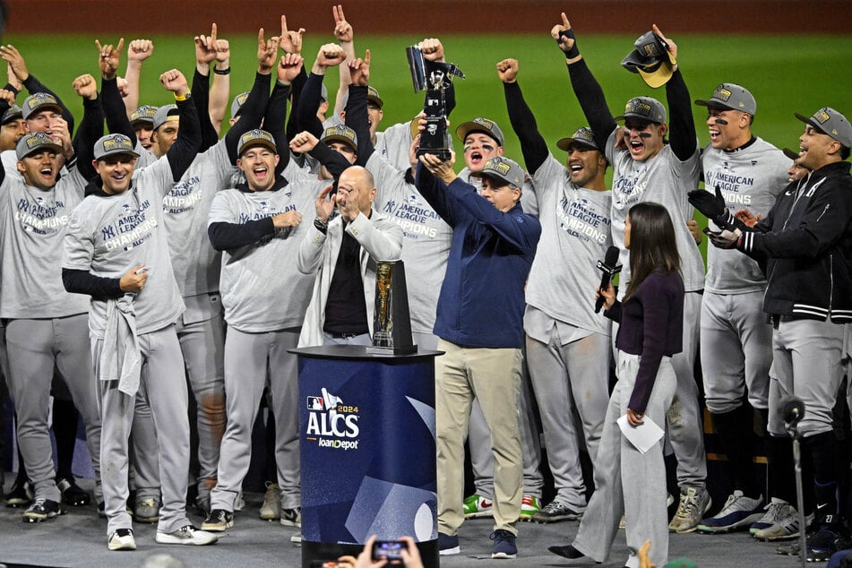 The New York Yankees celebrate with the American League Championship trophy after beating the Cleveland Guardians during game five of the ALCS.