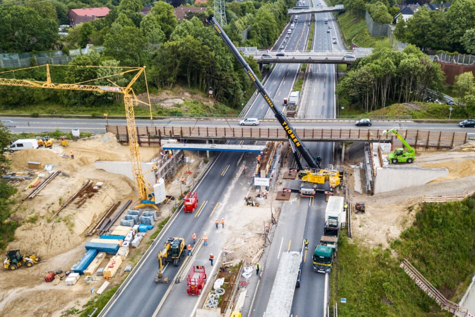 Techniker heben einen Fertigteilträger für eine Brücke über die A1 ein.