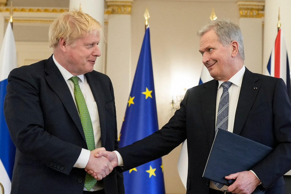 Der britische Premierminister Boris Johnson (l.) und der finnische Präsident Sauli Niinistö reichen sich die Hand.