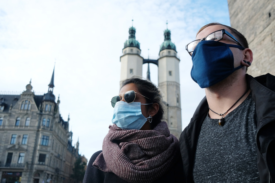 Passanten mit Mund- und Nasenschutz auf dem Marktplatz in Halle. Sachsen-Anhalts Bürger sind mehrheitlich gegen eine Steuererhöhung, um die Folgen der Corona-Pandemie zu stemmen.
