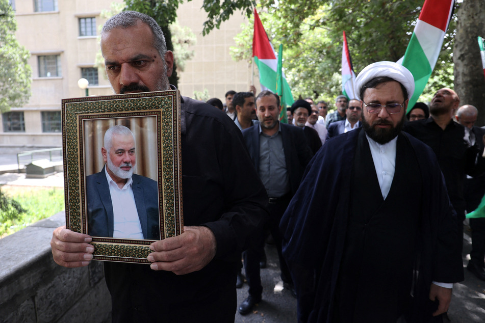 An Iranian man holds a picture of Hamas' slain political leader Ismail Haniyeh.